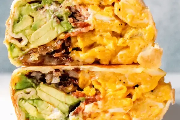 Delicious fluffy scrambled eggs, freshly sliced avocado, thick-cut crispy bacon, melted american yellow cheddar cheese, golden crisp hash brown, house-made aioli, and a hint of maple syrup, all wrapped in a warm flour tortilla.