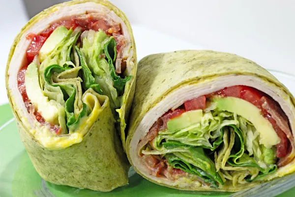 Enjoy a warm flour tortilla spread with creamy mayo and bold Dijon mustard, filled with antibiotic-free turkey, savory ham, crispy thick-cut bacon, fleshly sliced tomatoes, American cheddar cheese, and fresh organic spring mix for a delightful crunch.