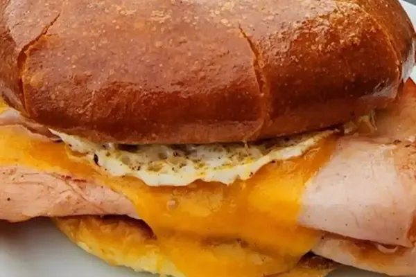 Savory grilled smoked sliced ham, fluffy scrambled eggs, melted American yellow cheddar cheese on a buttery brioche bun.