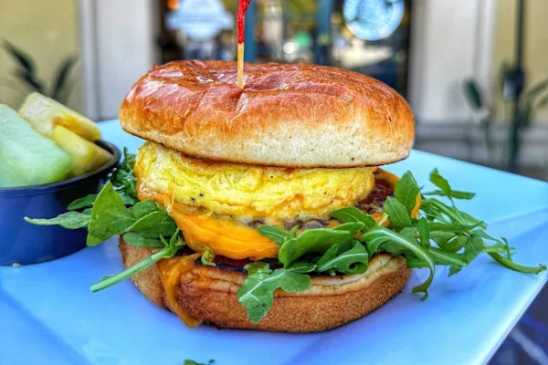 Featuring a Boar’s Head sausage patty, fluffy scrambled eggs, melted American yellow cheddar cheese, fresh organic arugula topped with our special house-made garlic aioli on a buttery brioche bun.